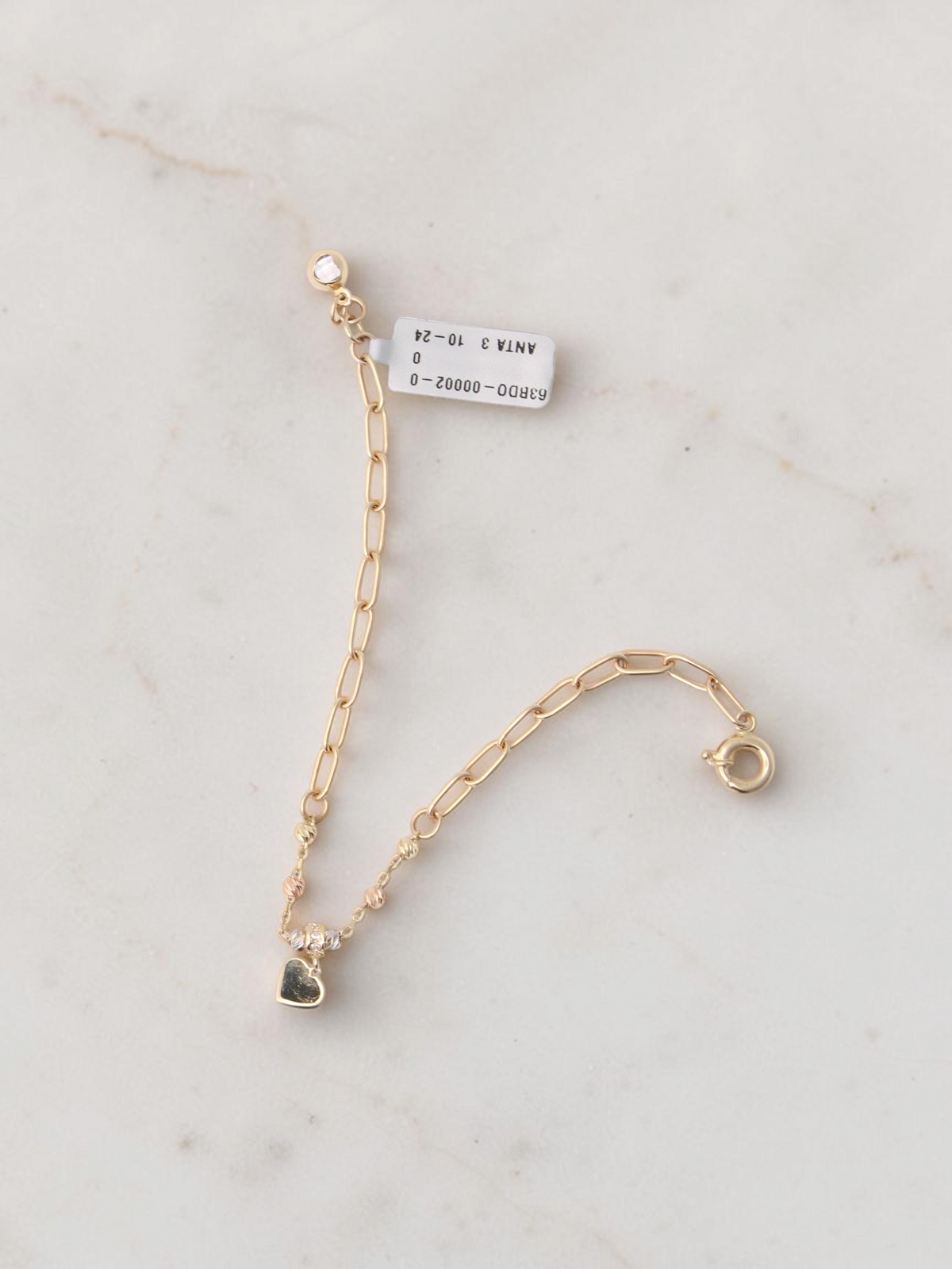 Zafrah paperclip chain bracelet in 14k tri-color gold with a small red enamel heart charm and adjustable clasp