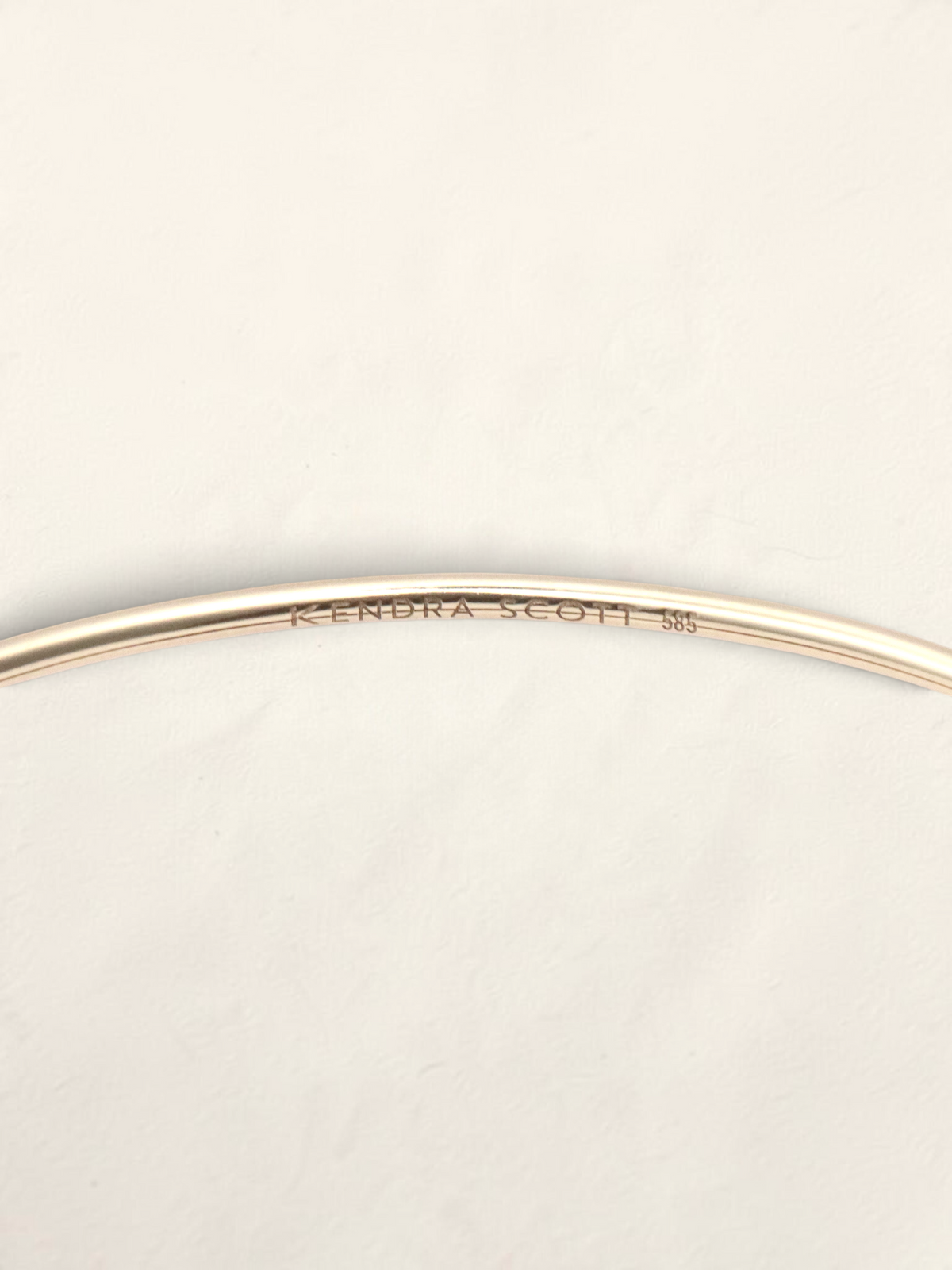 Zafrah 14K yellow gold Kendra Scott bangle showing the interior hallmark engraving
