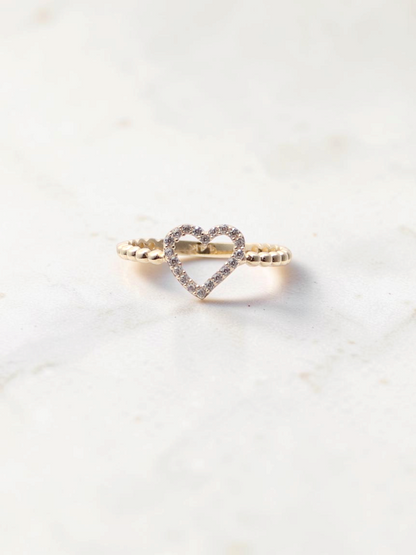 Zafrah 14k yellow gold heart ring featuring a beaded band and sparkling CZ stones on a marble surface.