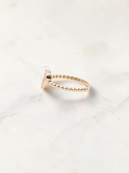 Zafrah 14k yellow gold heart bead ring with sparkling CZ stones on a white marble surface