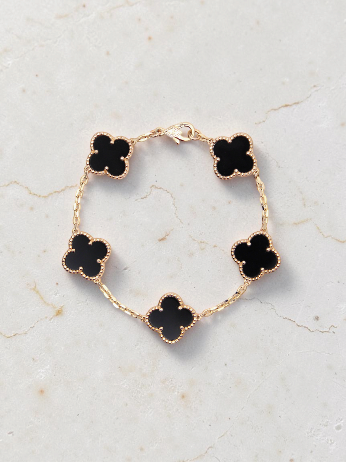 Zafrah 14k yellow gold bracelet featuring five black onyx clover motifs on a delicate chain, 7-inch length.