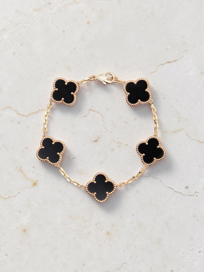 Zafrah 14k yellow gold bracelet featuring five black onyx clover motifs on a delicate chain, 7-inch length.