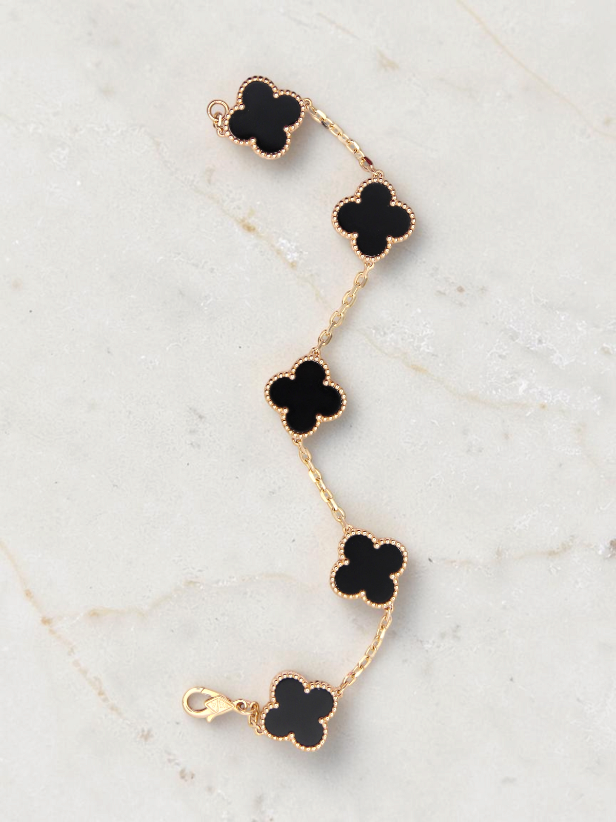 Zafrah 14k yellow gold bracelet featuring five black onyx clover motifs on a delicate chain