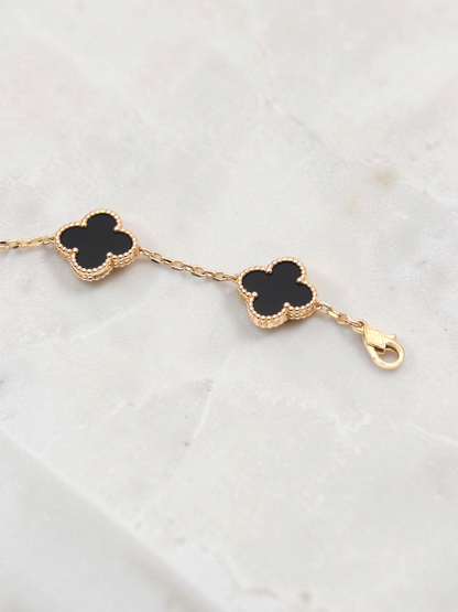 Zafrah 14k yellow gold bracelet featuring black onyx clover motifs with beaded edges and a lobster clasp closure.