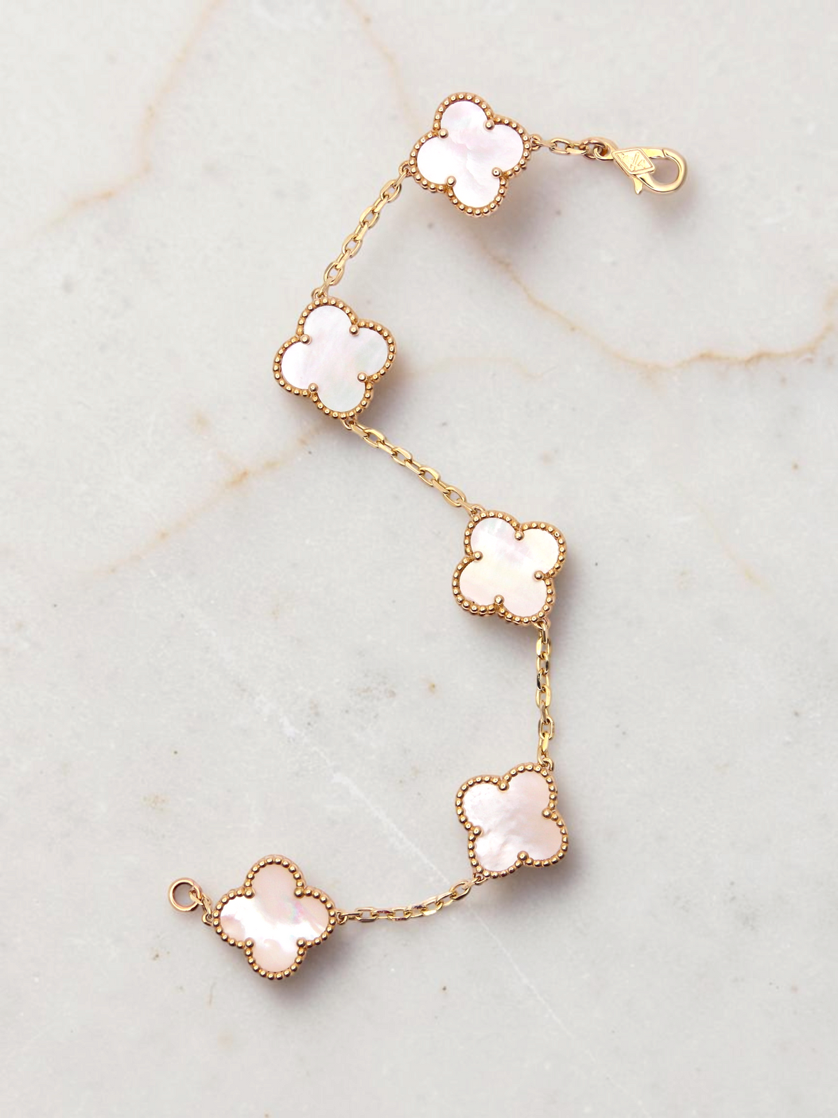Zafrah 14k yellow gold bracelet featuring five white mother of pearl clover motifs on a delicate chain.