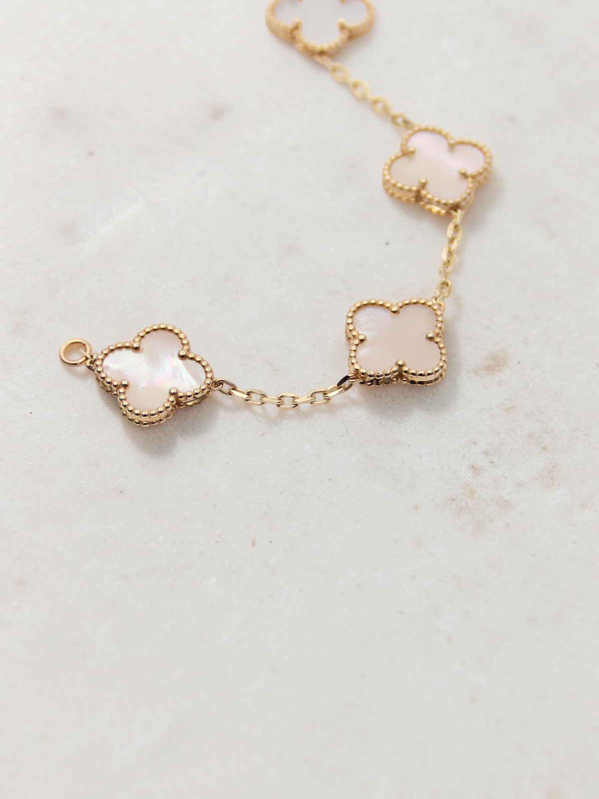 Zafrah 14k yellow gold bracelet featuring five iridescent mother of pearl clover motifs on a delicate chain.
