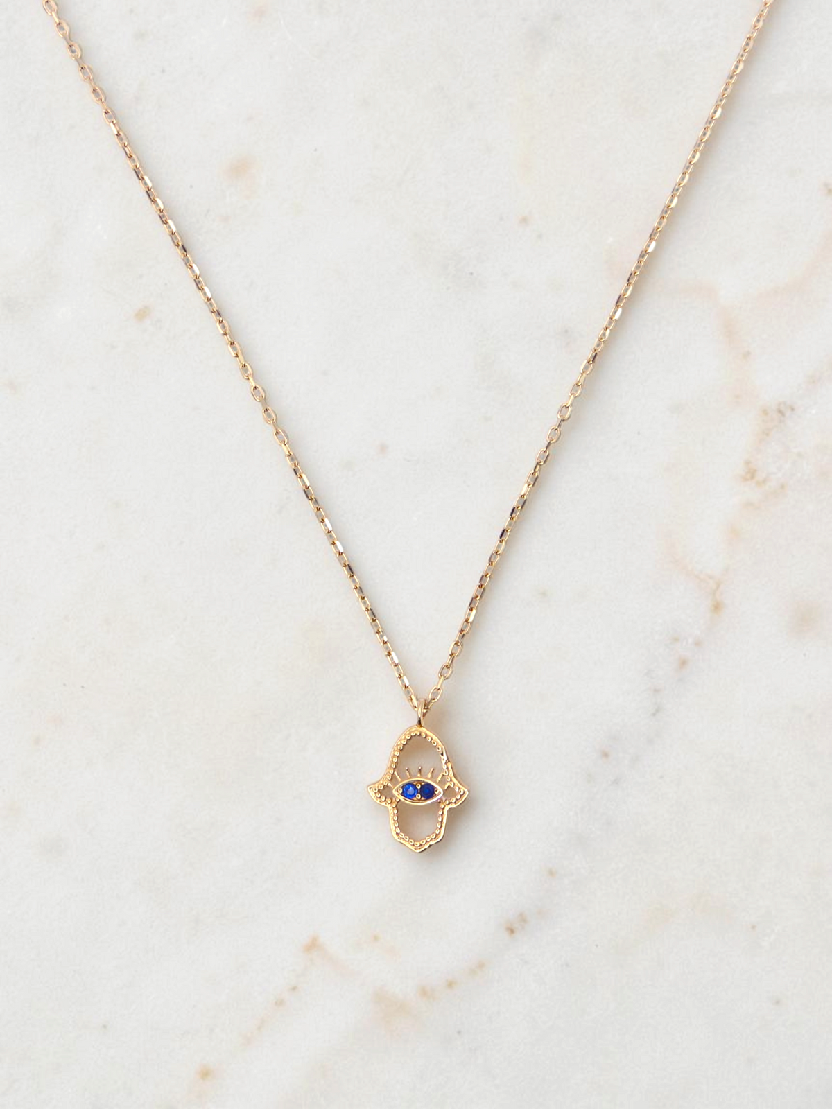 Zafrah 14k yellow gold hamsa eye pendant necklace with two blue stones on a delicate round link chain