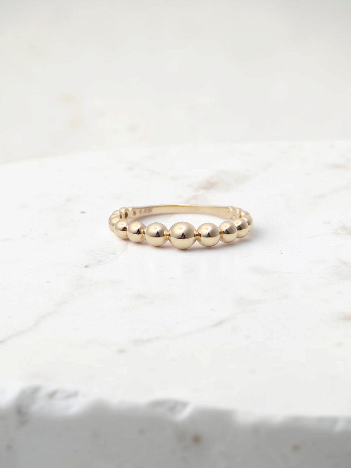 Zafrah 14k yellow gold beaded stacker ring with a polished finish on a white display block