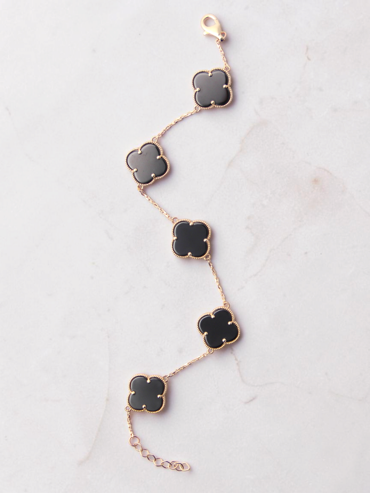 Zafrah gold bracelet featuring five black onyx clover motifs on a delicate chain with an adjustable lobster clasp.