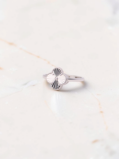 Zafrah 14k white gold Guilloché clover ring with intricate sunburst engraving on a marble surface.