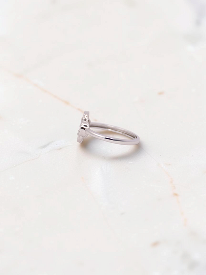 Zafrah 14k white gold Guilloché clover ring viewed from the side on a marble surface.