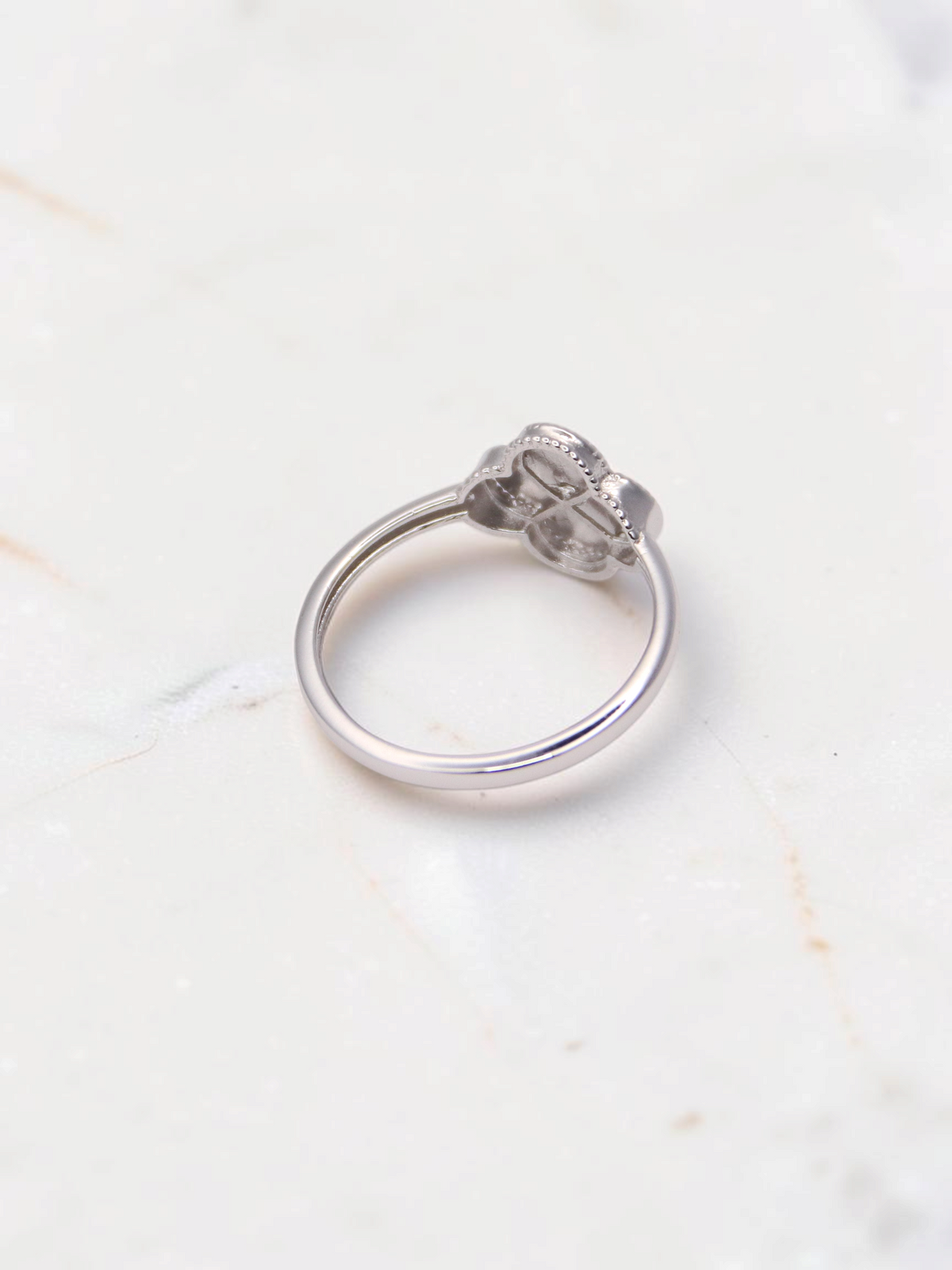 Zafrah 14k white gold Guilloché clover ring with intricate detailing on a marble surface
