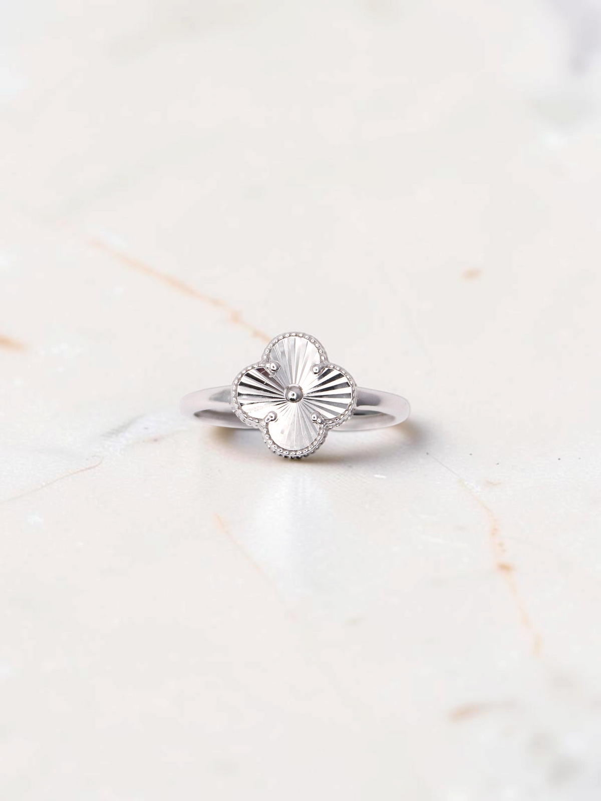 Zafrah 14k white gold clover ring featuring a detailed guilloché pattern on a polished band.