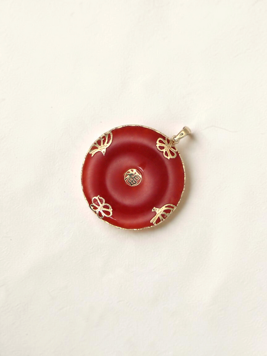 Zafrah 14K yellow gold pendant featuring a circular red jade stone with intricate gold filigree and a central symbol.