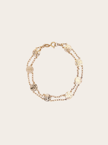 Zafrah 14K yellow gold station bracelet featuring circular Chinese good fortune symbols on a delicate double chain.