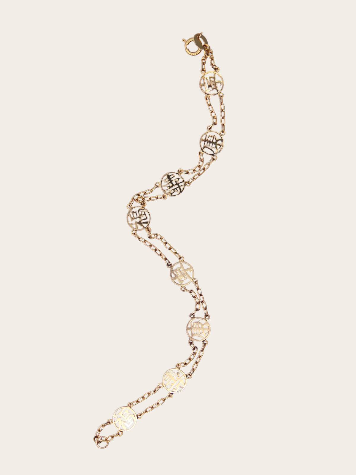 Zafrah 14K yellow gold station bracelet featuring circular Chinese good fortune symbols on a delicate double chain