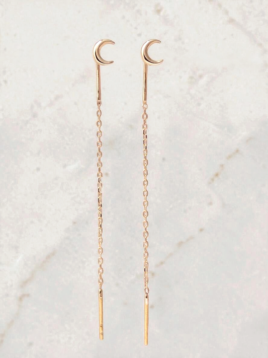 Zafrah 14k yellow gold crescent moon threader earrings with a delicate chain design on a marble background.