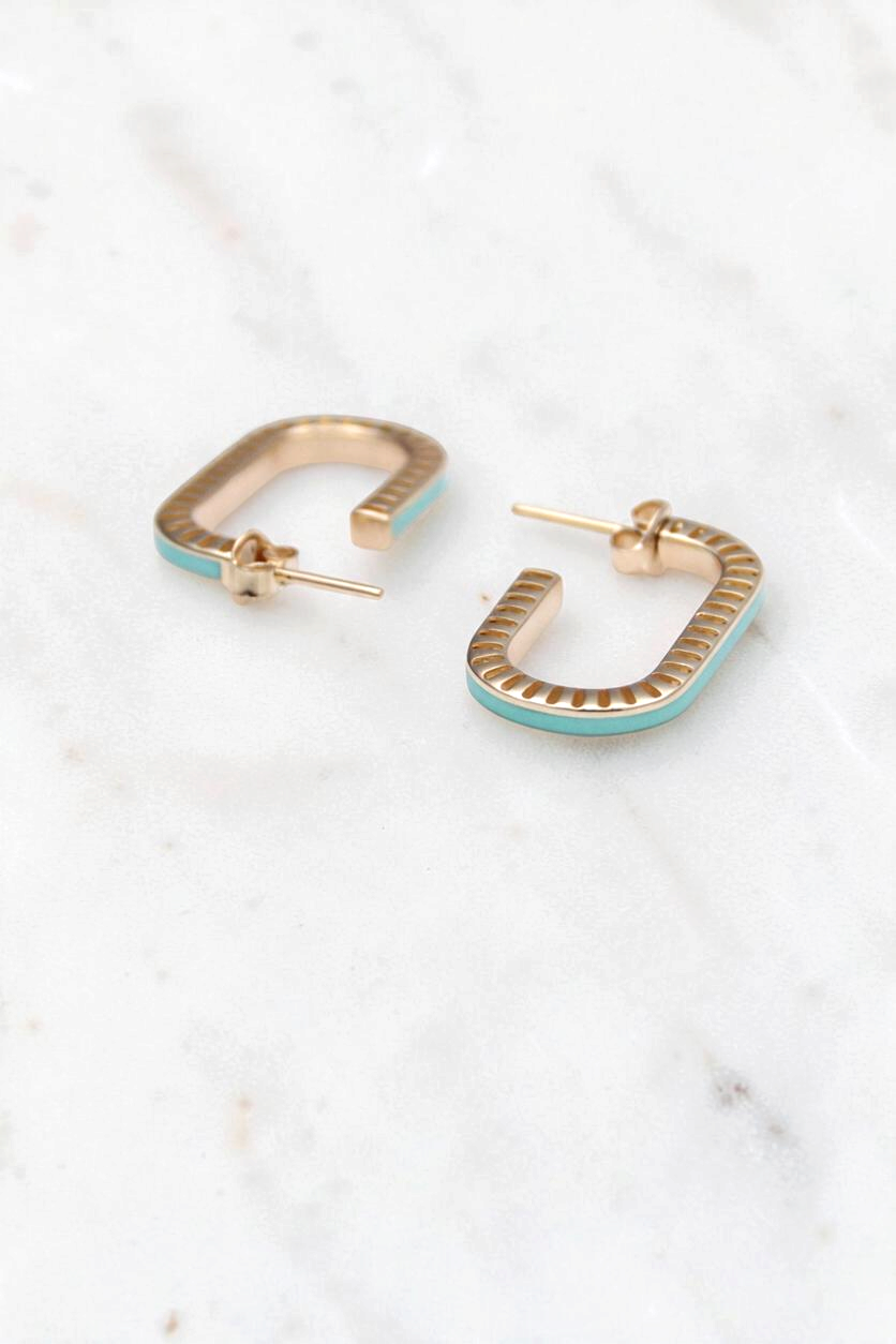 Zafrah 14k gold rectangular stud earrings with curved edges and turquoise enamel inlay on a white marble surface.