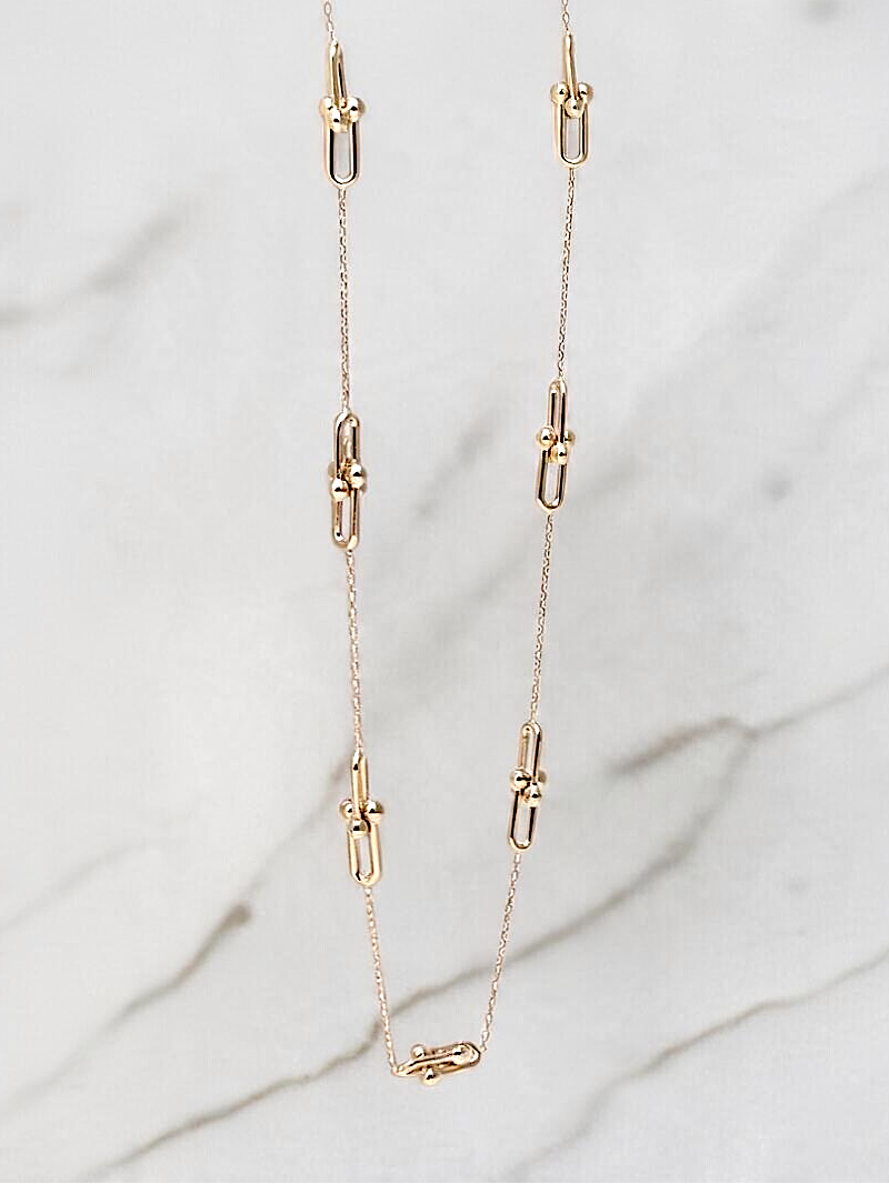 Zafrah 14k yellow gold beaded paperclip chain necklace with adjustable length on a marble background