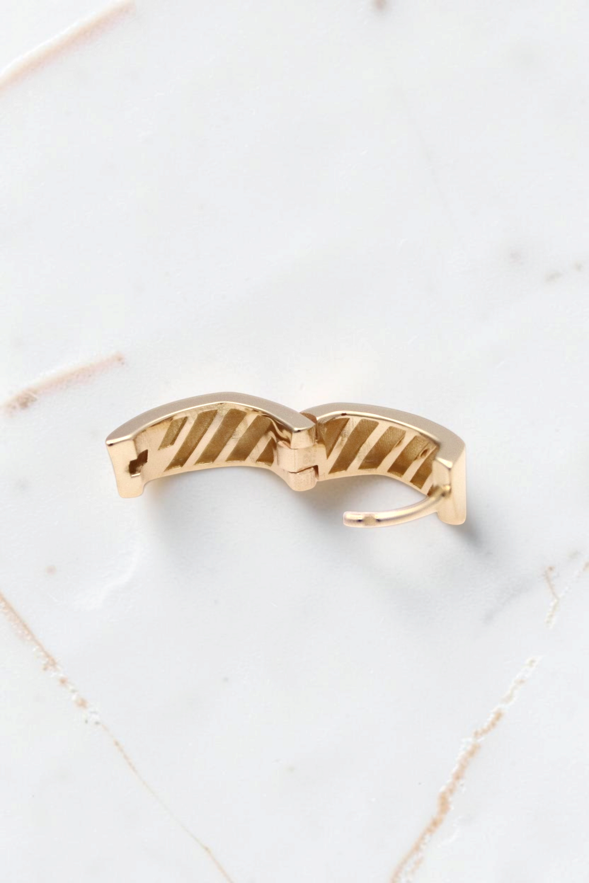 Zafrah 14k solid gold thick rectangle huggie hoop earrings with a textured interior design on a white background.