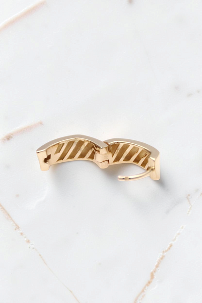 Zafrah 14k solid gold thick rectangle huggie hoop earrings with a textured interior design on a white background.