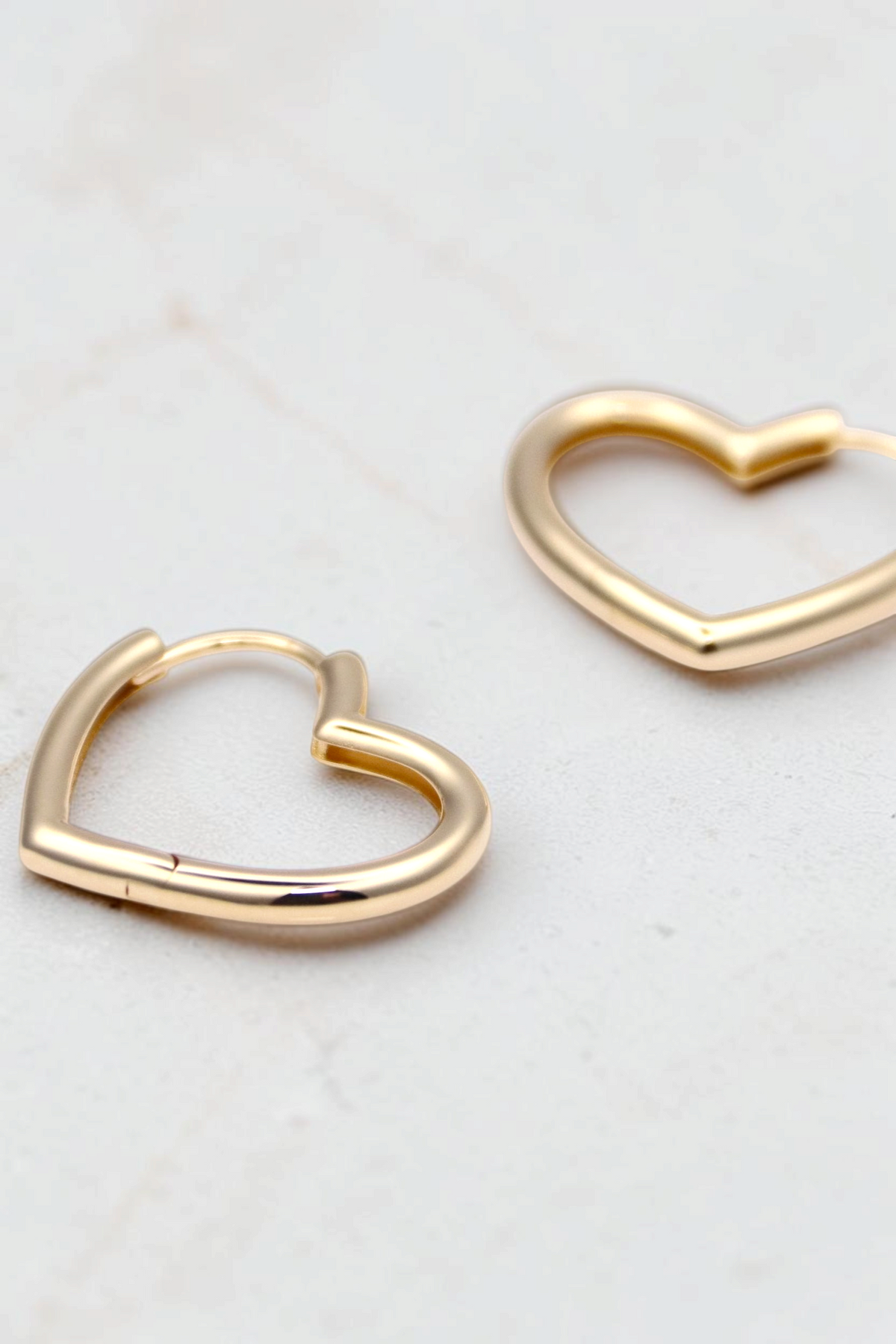 Zafrah 14k solid gold heart-shaped huggie earrings with a polished finish on a white background.