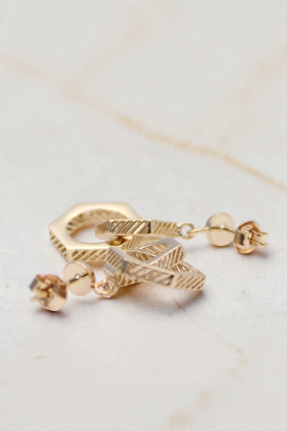 Zafrah 14k solid gold double hexagon drop earrings with industrial textured detailing on a white background.
