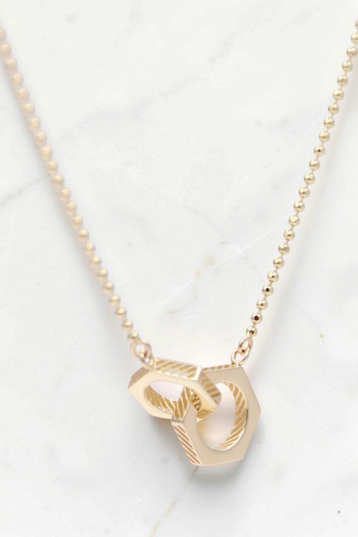 Zafrah 14k solid gold necklace featuring two interlocking hexagon beads on a delicate beaded chain