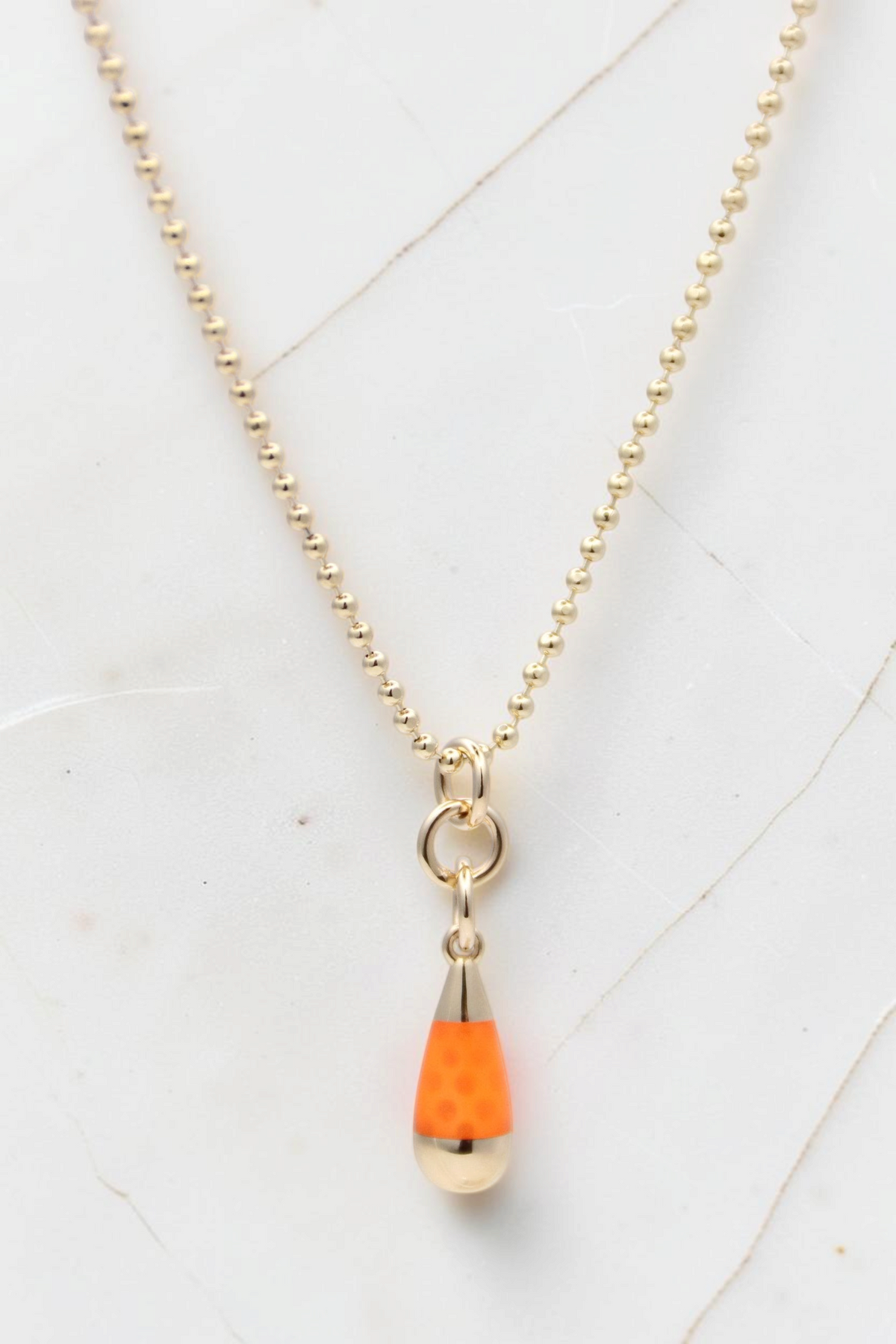 Zafrah 14k solid gold beaded chain necklace featuring an orange and blue drop pendant on a white marble background