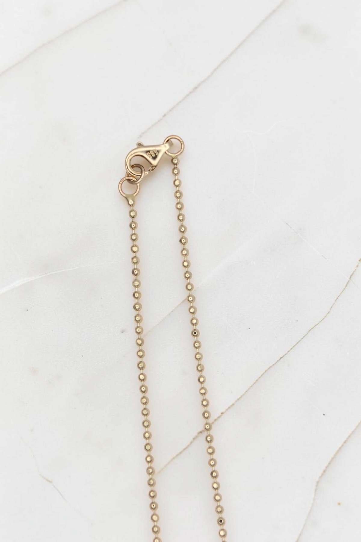 Zafrah 14k solid gold beaded chain necklace with lobster clasp closure on a white marble surface