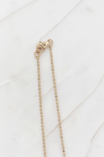 Zafrah 14k solid gold beaded chain necklace with lobster clasp closure on a white marble surface