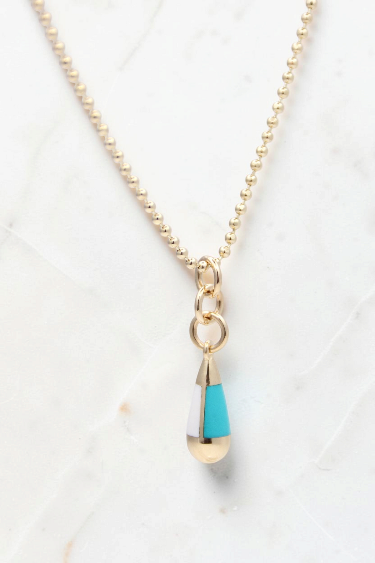 Zafrah 14k gold beaded chain necklace featuring a turquoise and white teardrop pendant on a light background