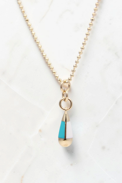 Zafrah 14k gold beaded chain necklace featuring a turquoise and white drop pendant on a light background.