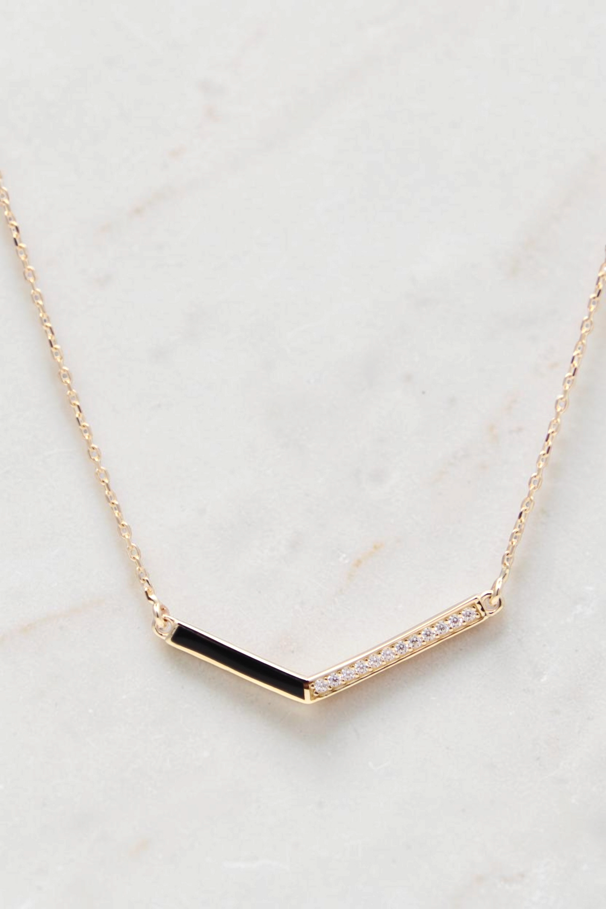 Zafrah 14k gold curb chain necklace featuring a V-shaped pendant with black enamel and sparkling diamond accents