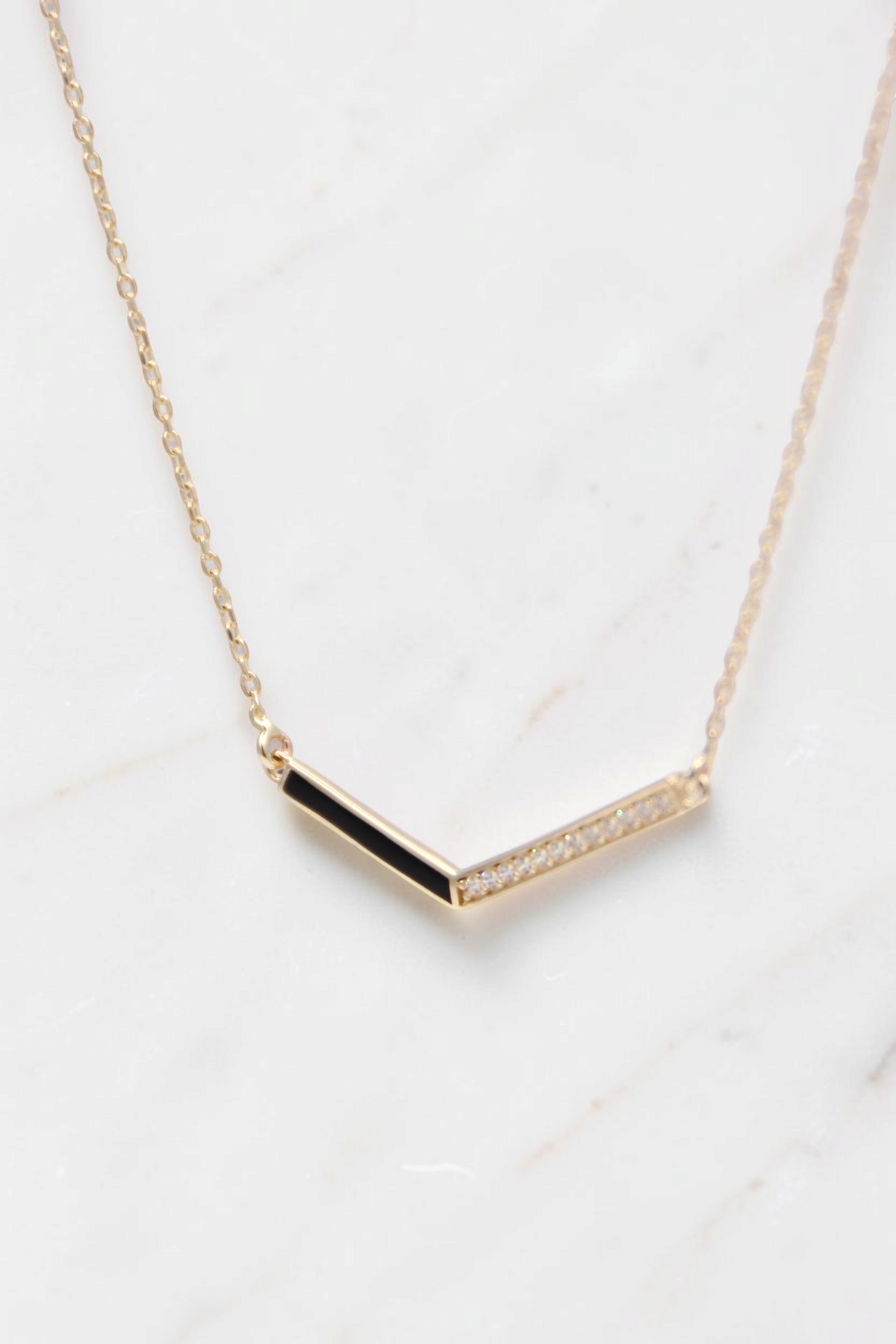 Zafrah 14k gold curb chain necklace featuring a V-shaped pendant with black enamel and sparkling pavé diamonds