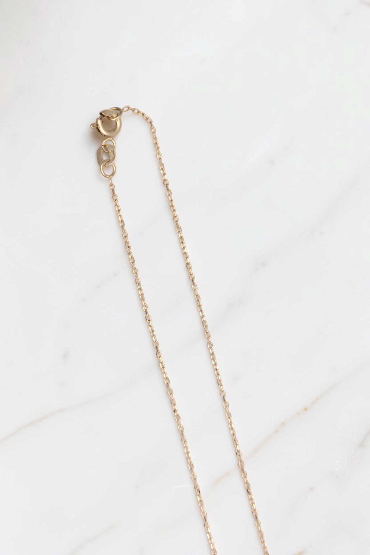 Zafrah 14k solid gold thin curb chain necklace with a delicate V-shaped pendant on a simple white background