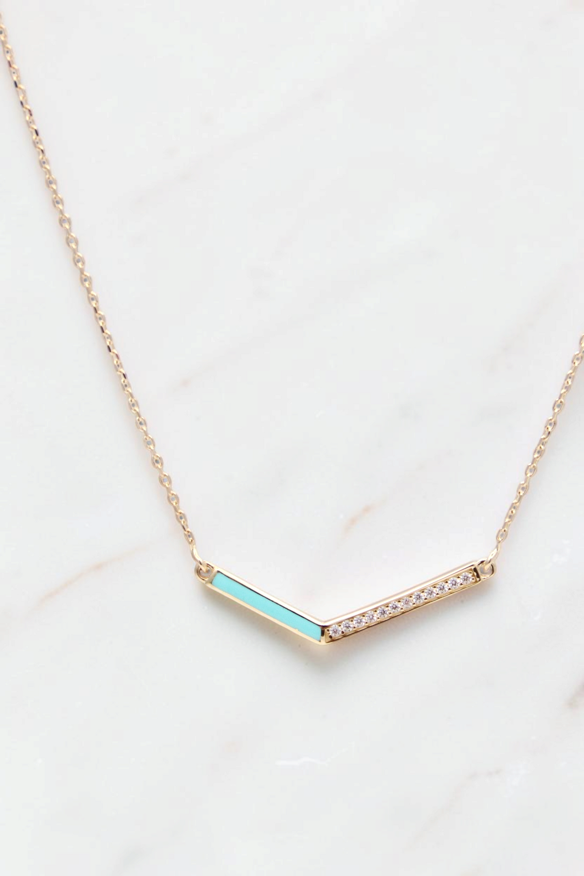 Zafrah 14k gold V-shaped pendant necklace featuring a turquoise enamel inlay and a row of sparkling diamonds.