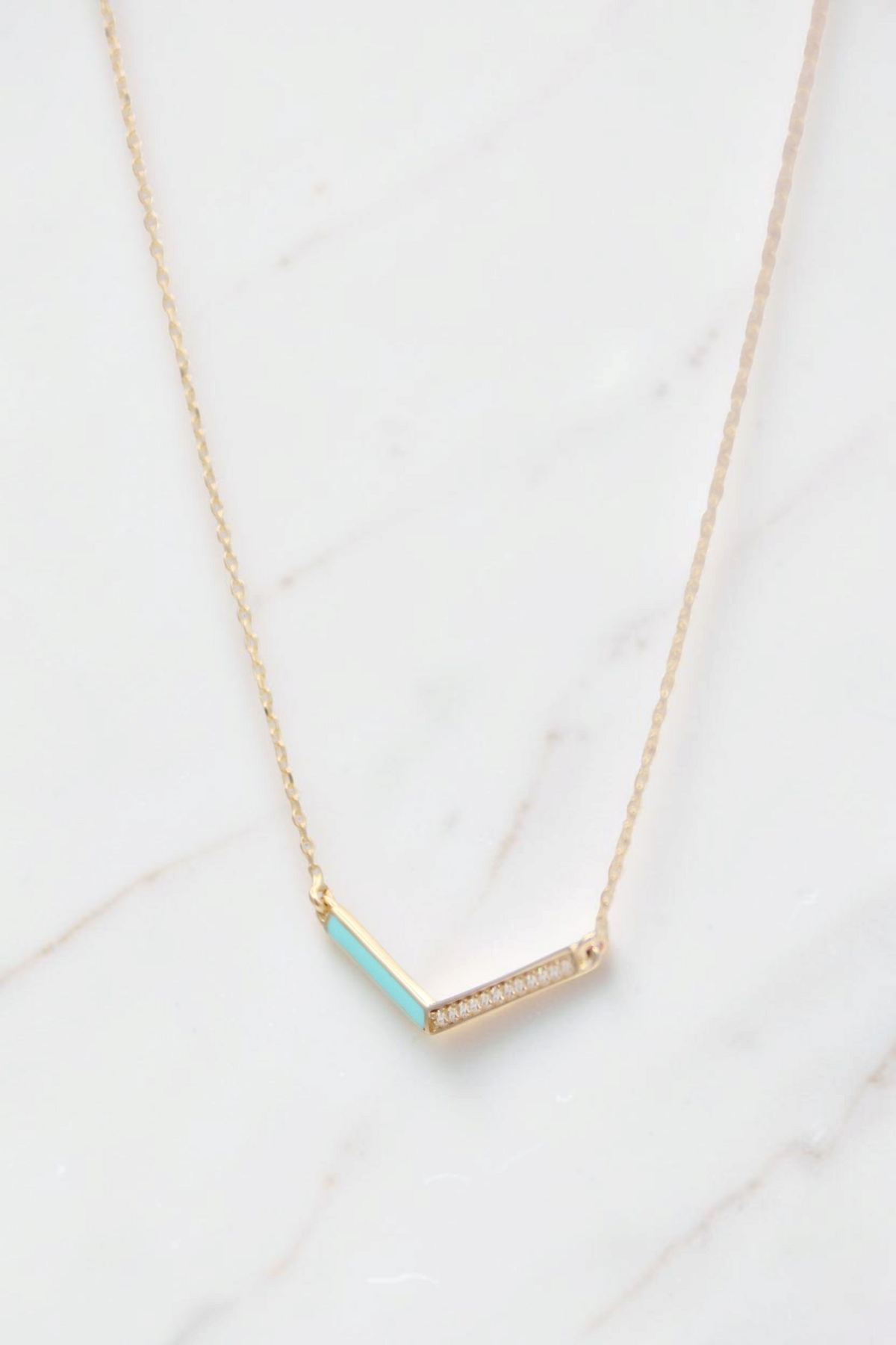 Zafrah 14k gold V-shaped pendant necklace featuring a turquoise inlay and delicate diamond accents on a curb chain.