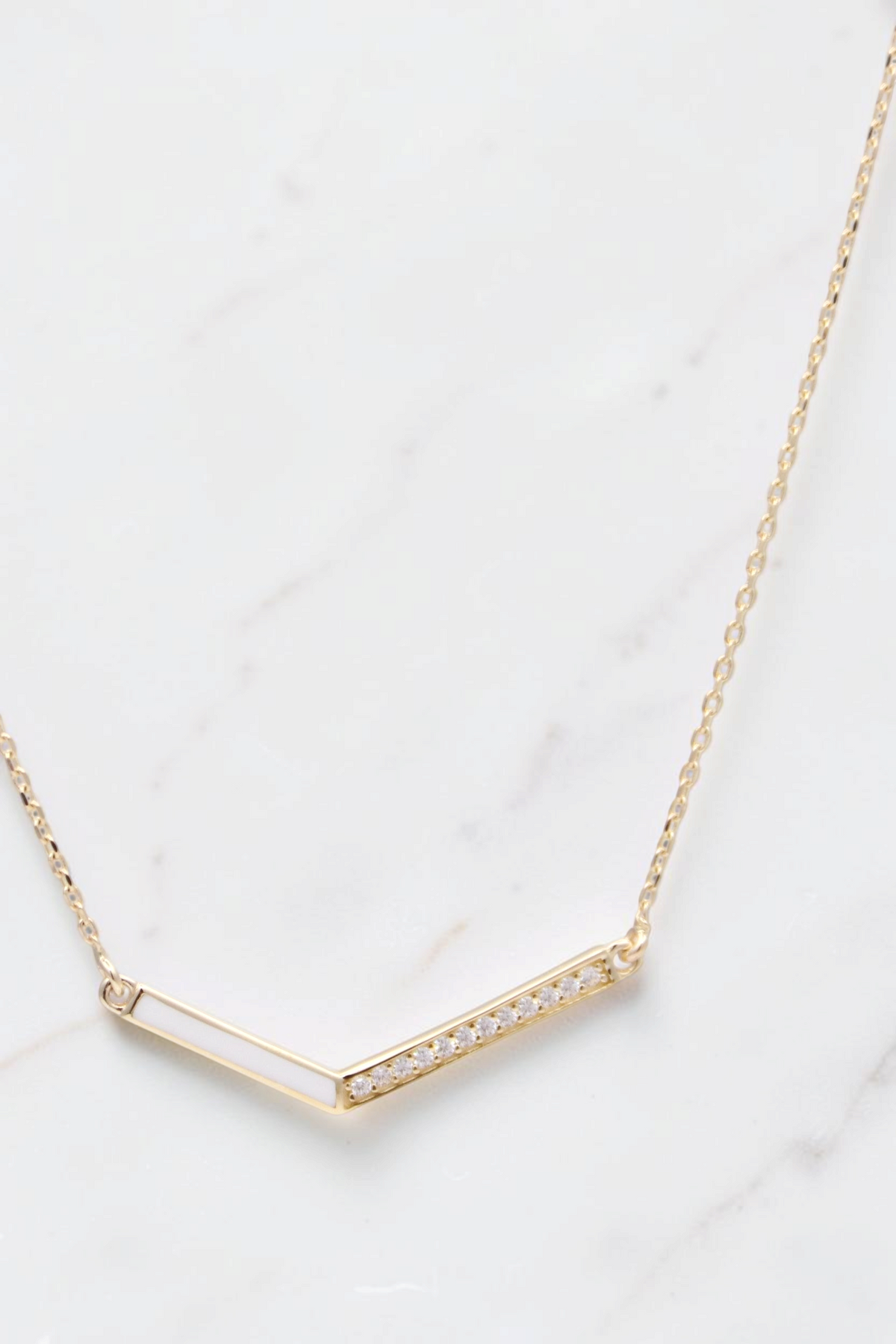 Zafrah 14k solid gold V-shaped pendant necklace on a thin curb chain with delicate stone accents