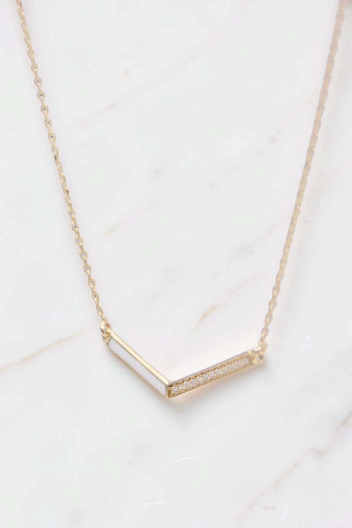 Zafrah 14k solid gold necklace featuring a delicate V-shaped pendant with small inset diamonds on a thin curb chain.