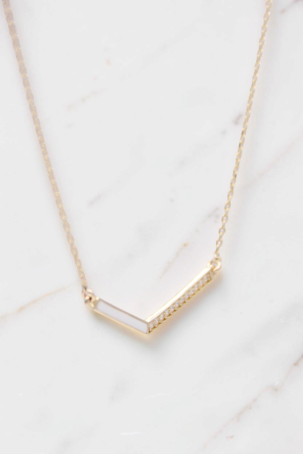 Zafrah 14k solid gold V-shaped pendant necklace on a thin 17-inch curb chain with delicate diamond accents.