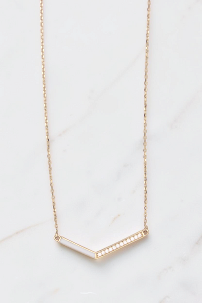 Zafrah 14k gold V-shaped pendant necklace featuring a thin curb chain, white inlay, and delicate diamond accents.