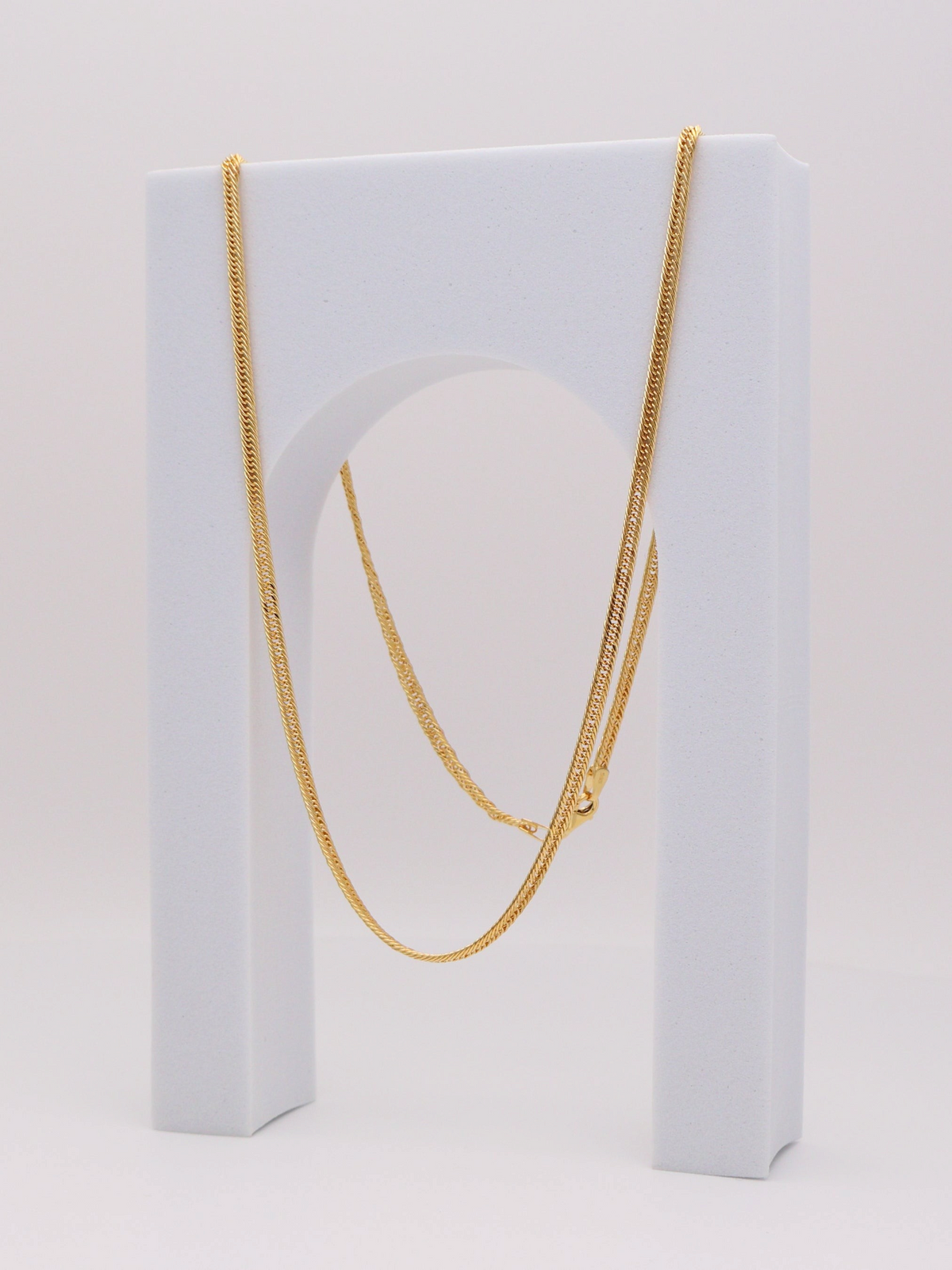 Zafrah 14k yellow gold 2.75mm snake chain necklace, 21.5 inches long, displayed on a white arch stand.