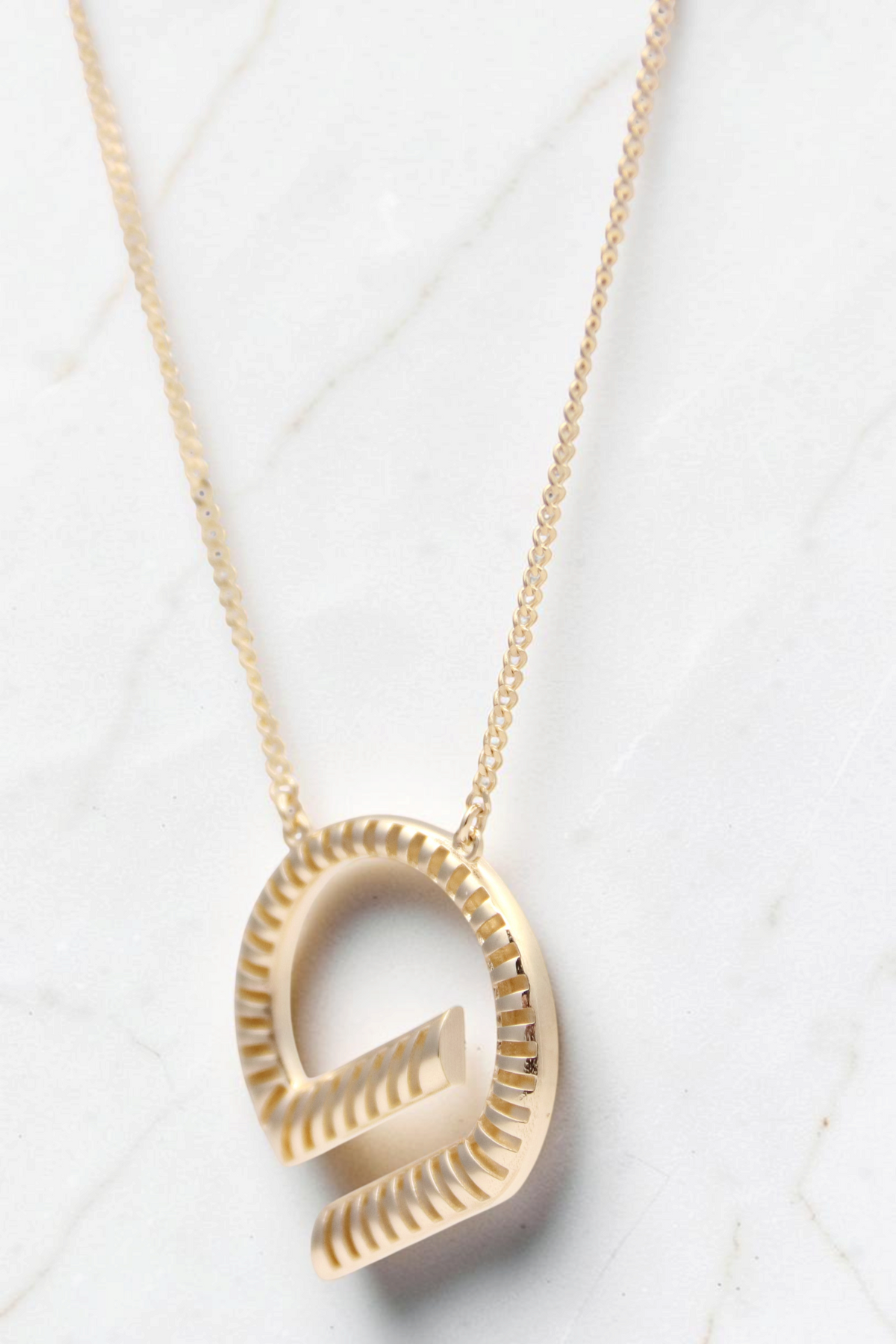 Zafrah 14k solid gold G-shaped pendant necklace featuring a textured circular design on an 18-inch curb chain.