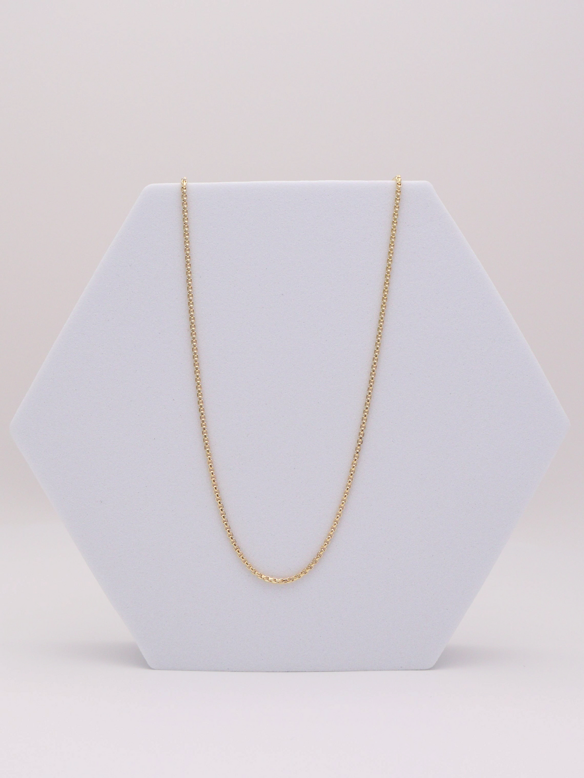 Zafrah 14k yellow gold 1mm square rolo chain necklace measuring 21.5 inches in length on a white hexagonal display.