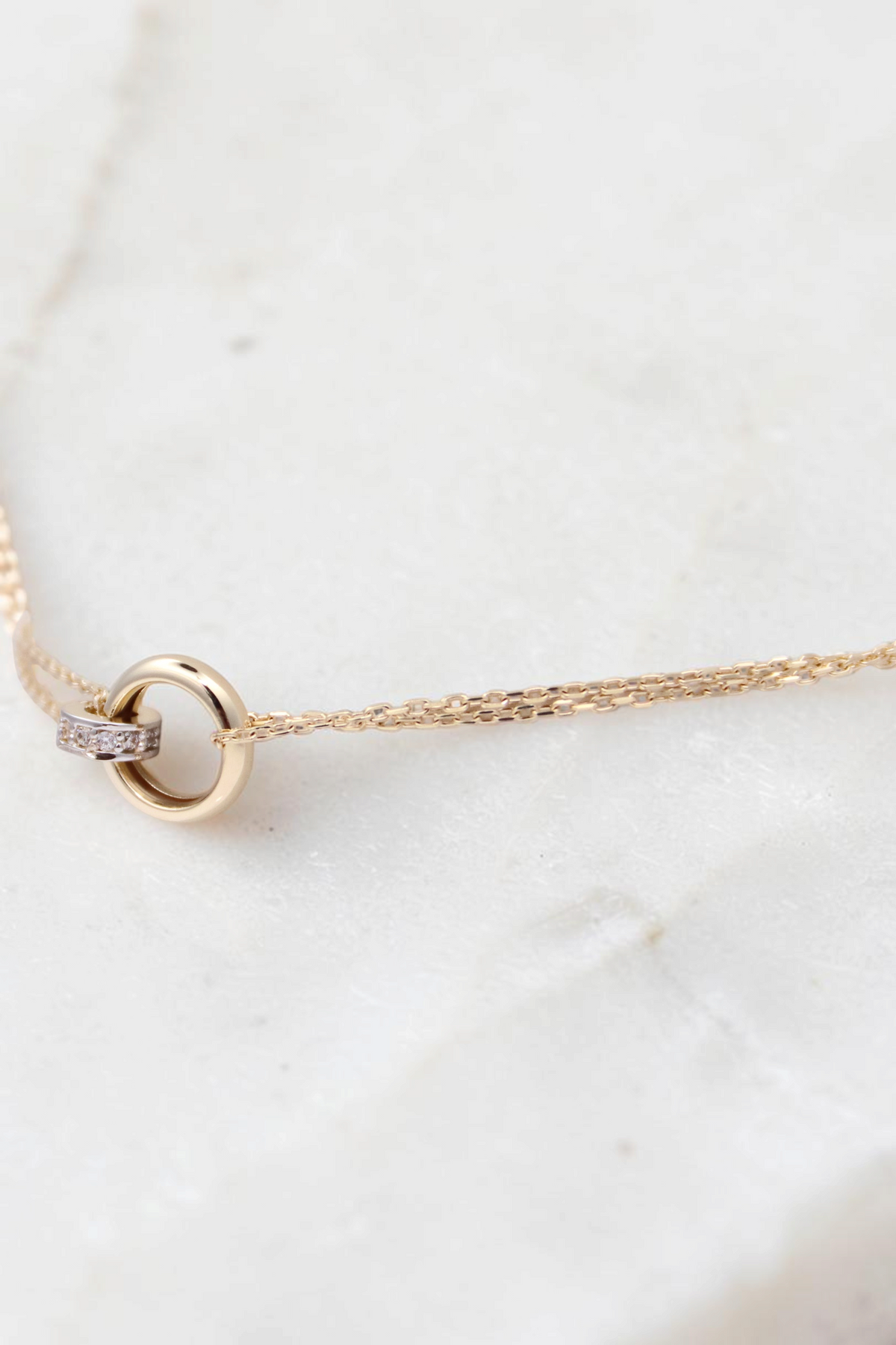 Zafrah 14k solid gold double cable bracelet featuring a round link with small diamond accents on a white display.