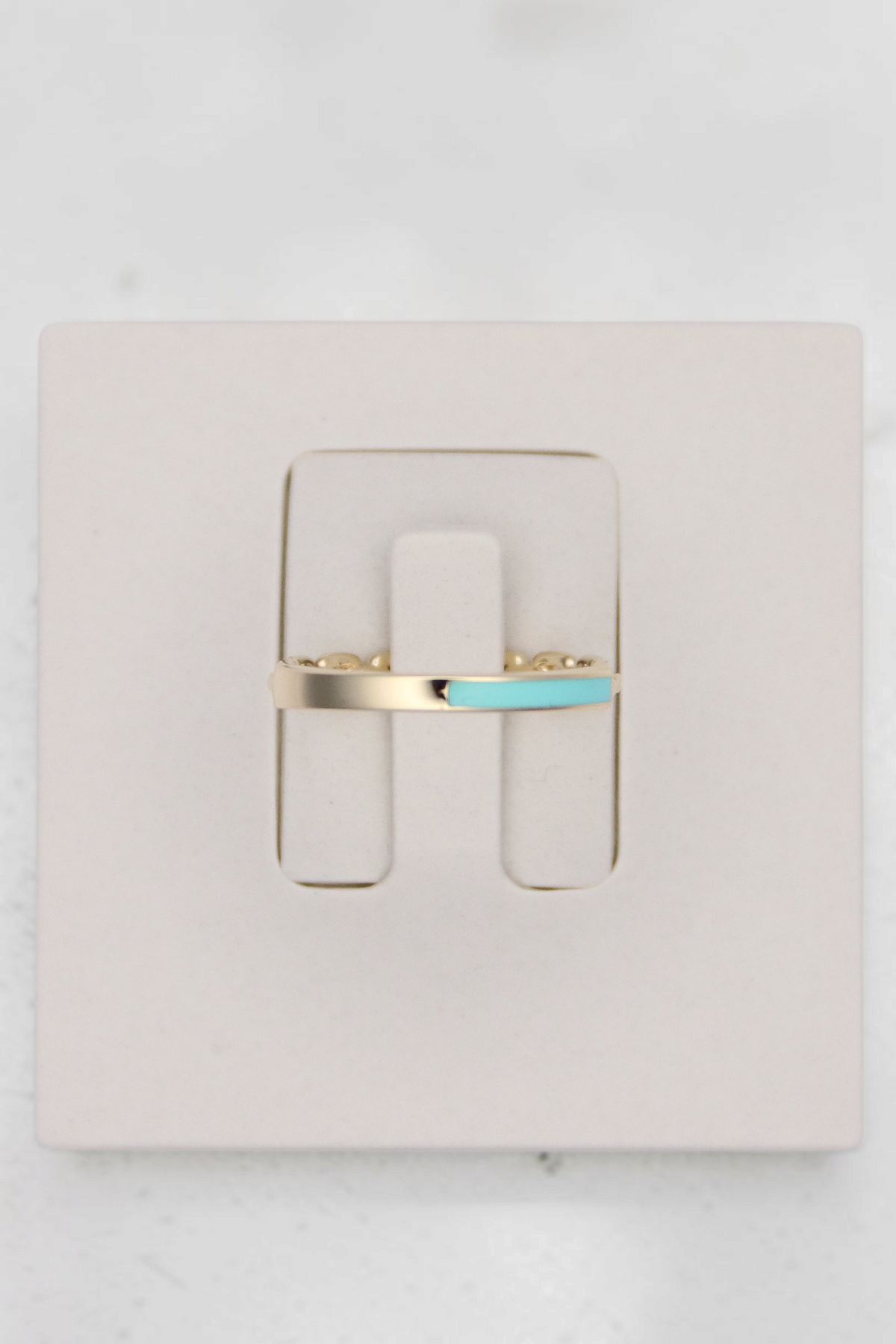 Zafrah 14k solid gold chain link ring featuring a vibrant turquoise enamel accent on a white display stand