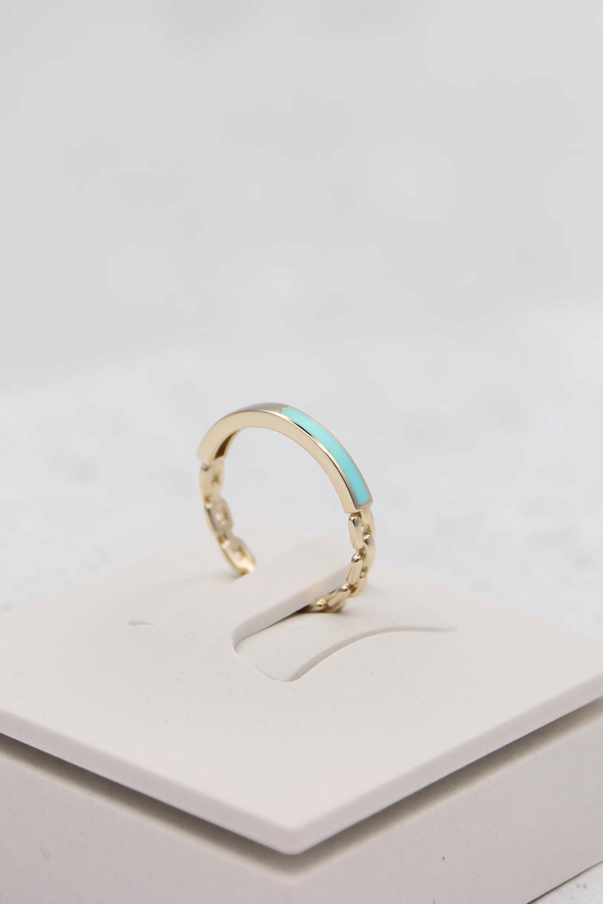 Zafrah 14k solid gold chain link ring featuring a delicate turquoise enamel inlay on a white display stand