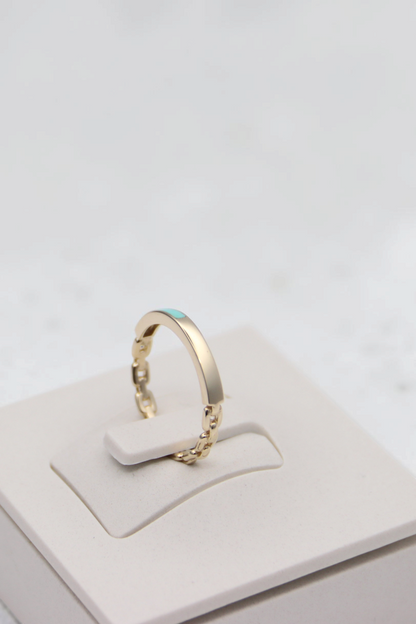 Zafrah 14k solid gold chain link ring with a small turquoise accent on a white display stand.