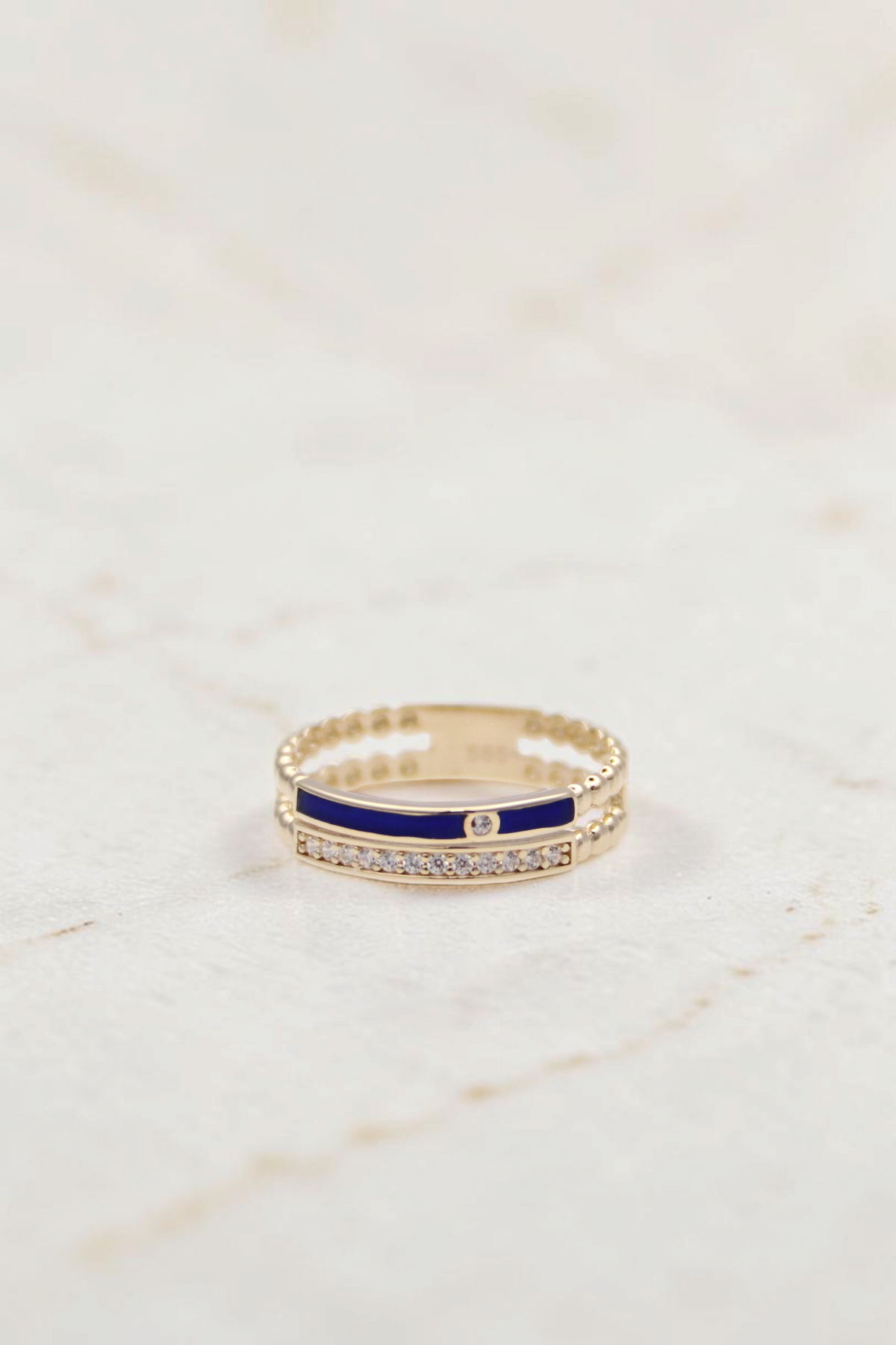 Zafrah 14k gold double band ring featuring a blue enamel stripe, clear stones, and beaded edges on a white background.